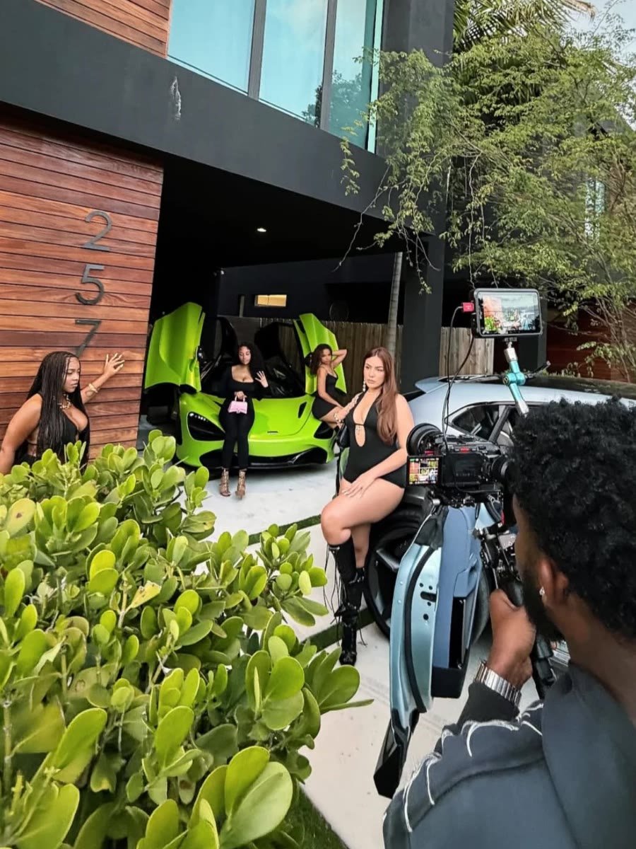 Luxxx models on a music video set with a lime green supercar and a camera operator