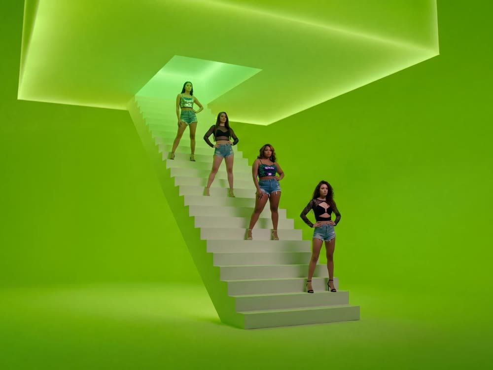 Four models posing on the white staircase in the green music video room